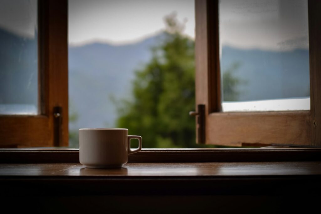 Xícara na janela com vista para as montanhas